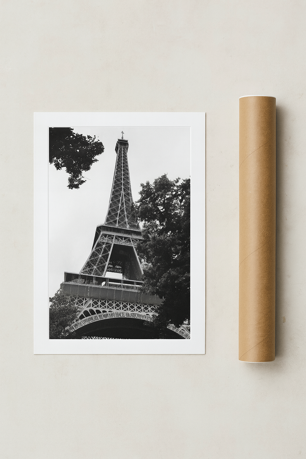 Framed black and white photo of the Eiffel Tower on a light gray background with a cardboard tube next to it.